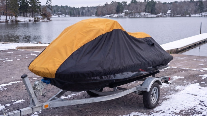 Jet ski on a trailer beside a snowy lake under a yellow and black AllGuard Weatherproof Shield cover