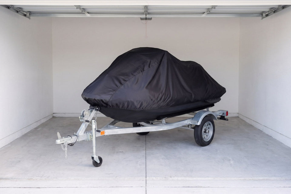 Sea-Doo Spark on its trailer under a black Satin Shield indoor cover, seen through the open door of a white-walled garage